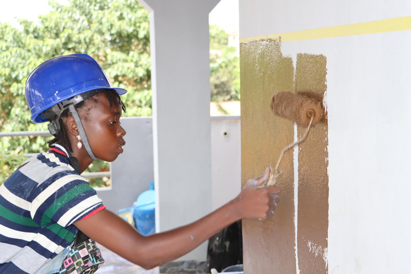 Eine Auszubildende zur Malerin streicht eine Wand.