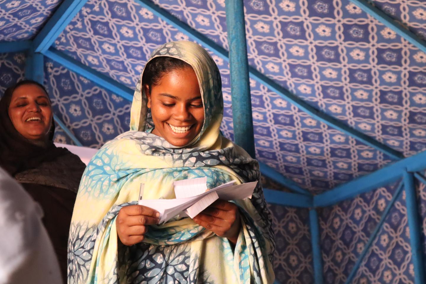 Frau hält Zettel in der Hand und lächelt nach unten