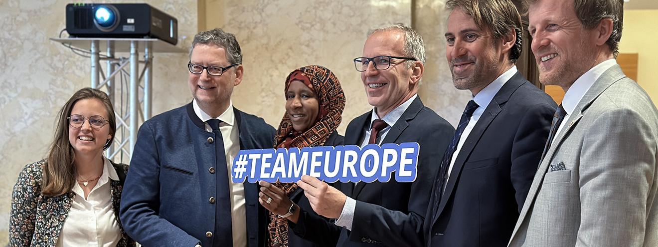 Six people posing together for a group photo, one person in the center holding a sign reading "#TEAMEUROPE".