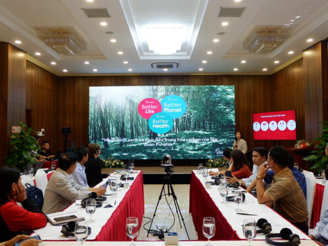 Group of people sitting at tables looking at a screen