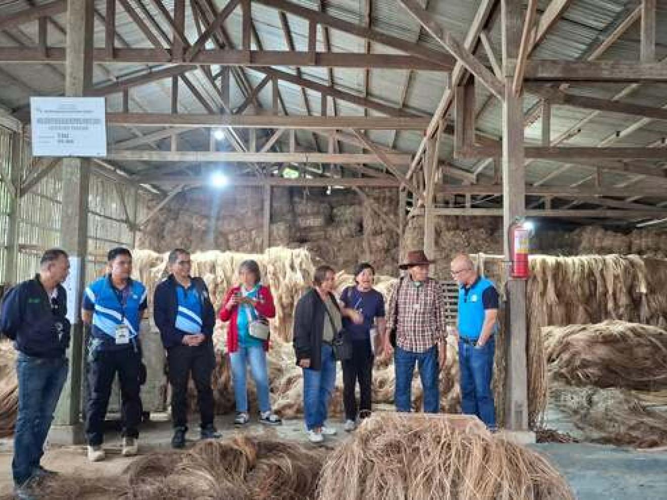 Vertreter:innen des Farmers Alternative for Self-Reliance Multi-Purpose Cooperative (FARSMCO) und GIZ in einer Scheune zwischen Strohballen.