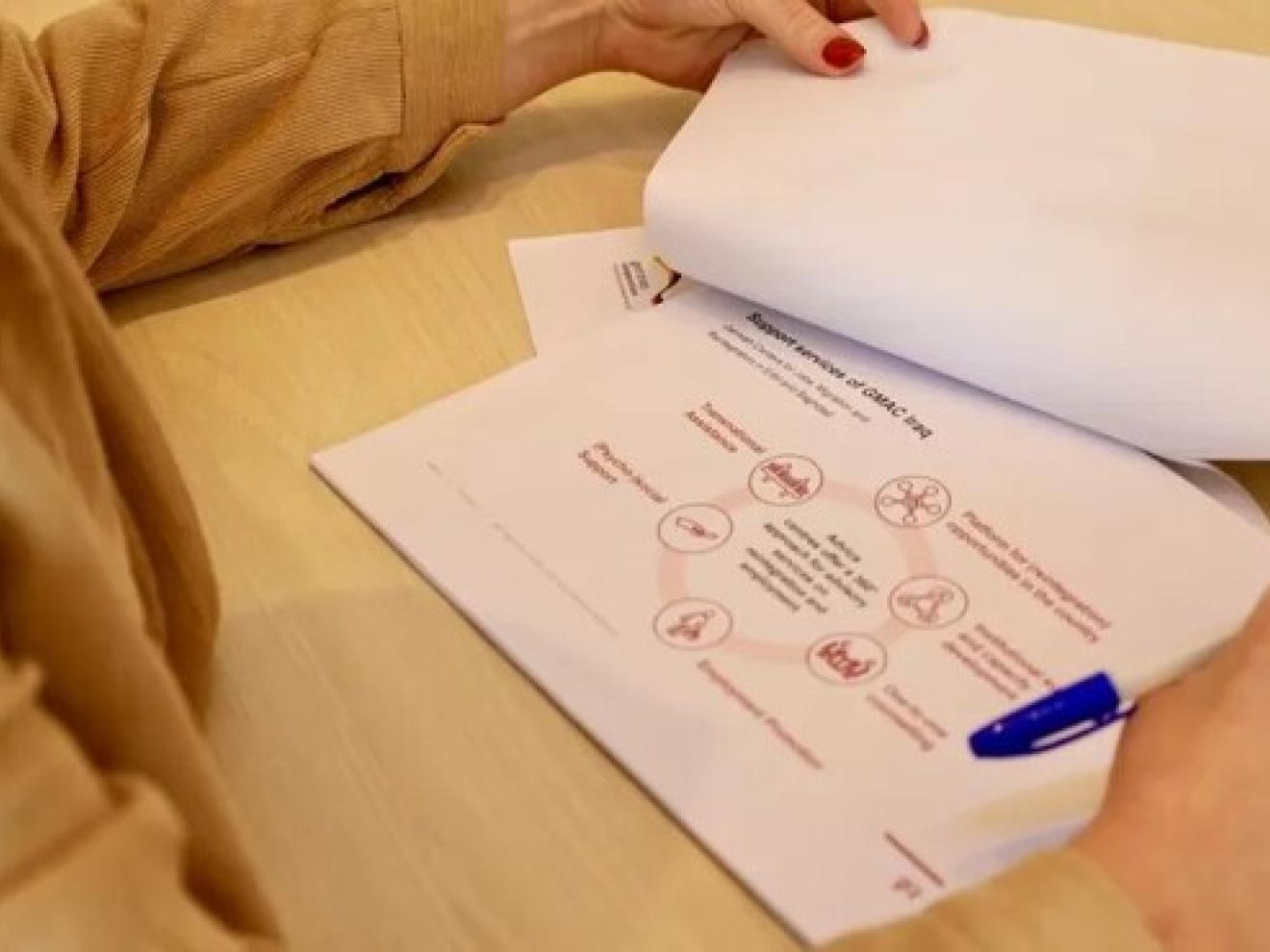 Hands holding paperwork lying on a desk