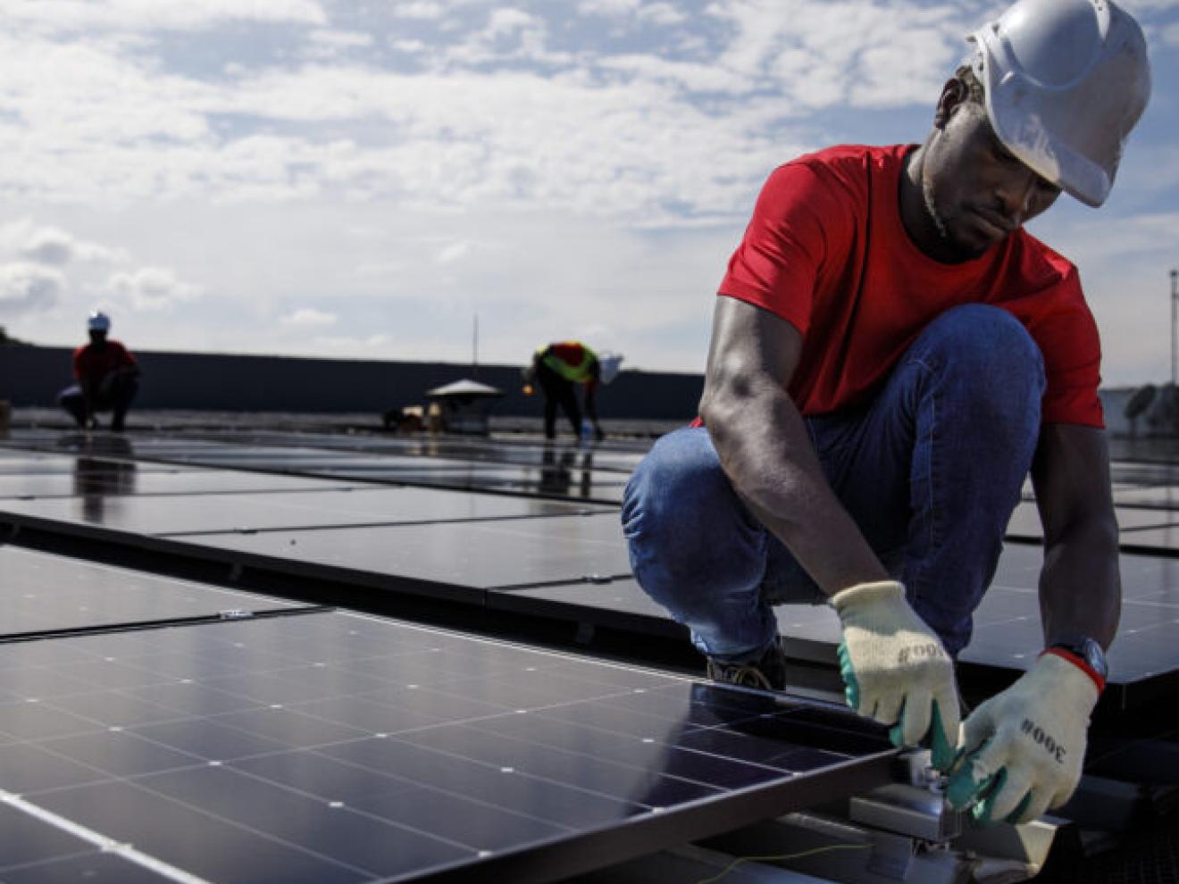 Ein Arbeiter bringt ein Solarpanel auf einem Dach an