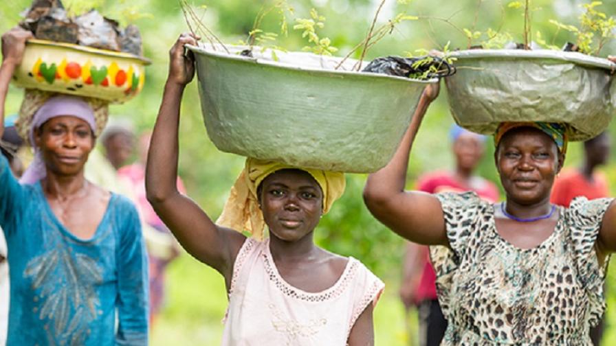 Several people carrying a bowl on their heads.