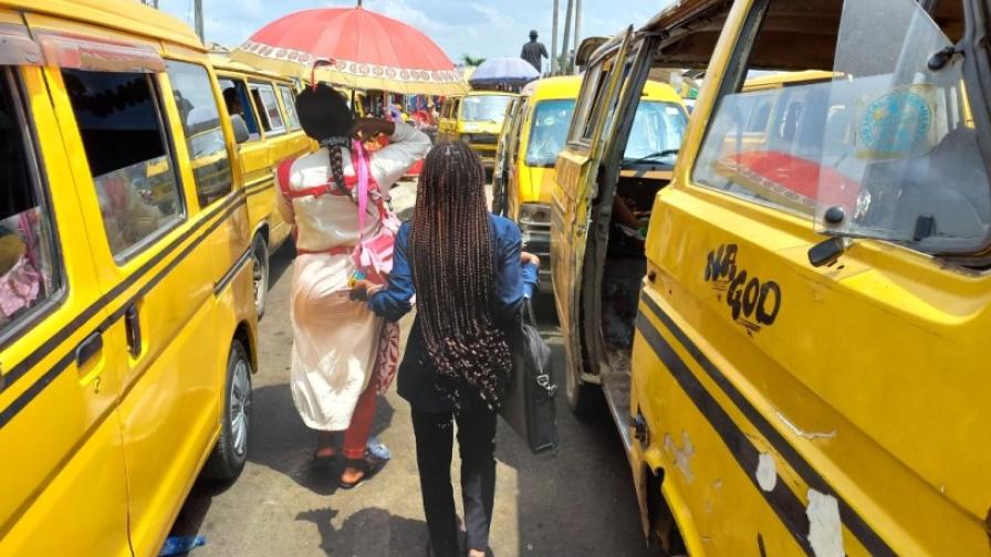 Two women walk between taxis.