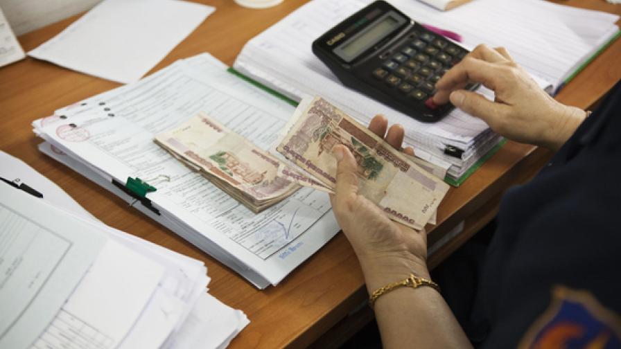 A person is counting money on a desk.