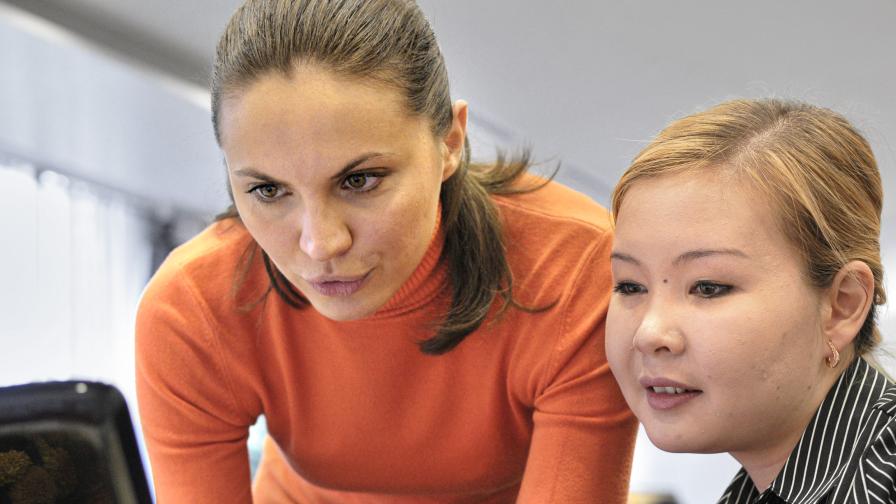 Zwei Männer blicken im Freien auf ein Blatt Papier 