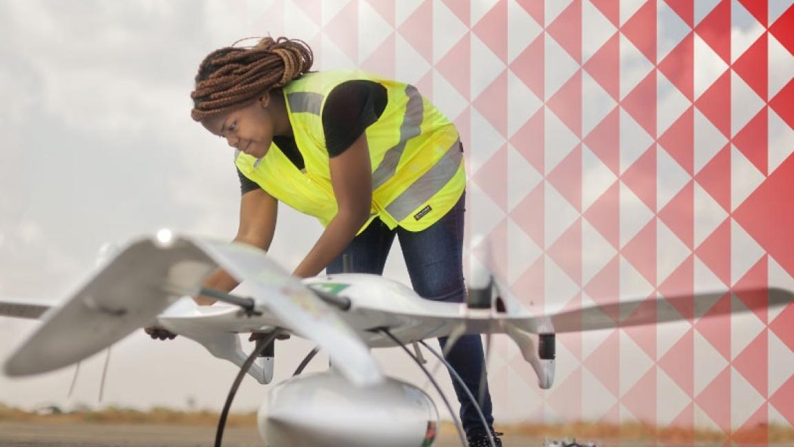 Eine Frau in einer Warnweste arbeitet an einer Drohne.