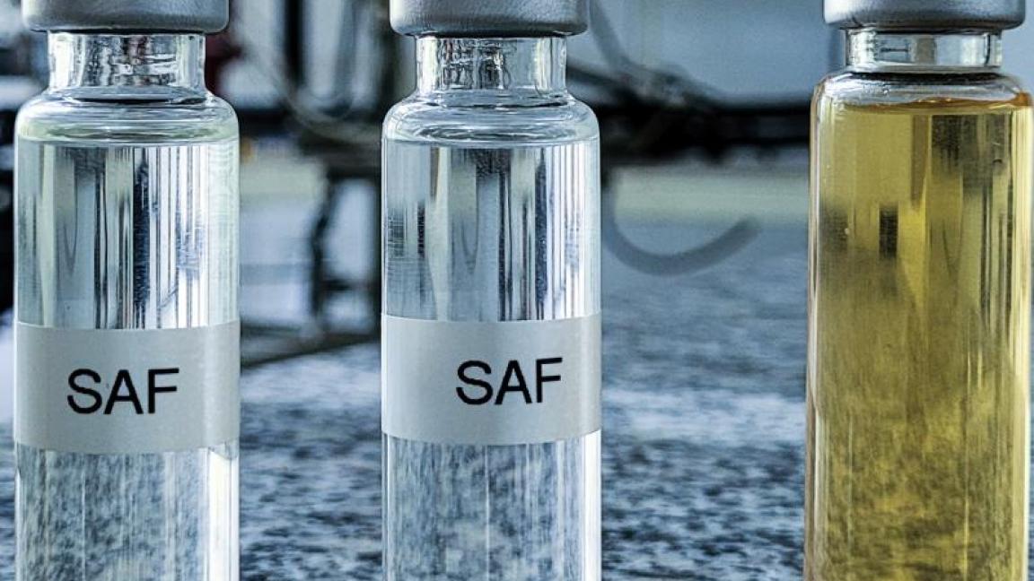 Mehrere Glasfläschchen mit Flüssigkeiten in verschiedenen Farben, beschriftet mit "SAF", stehen in einer Reihe auf einer Granitplatte in einem Laborumfeld.