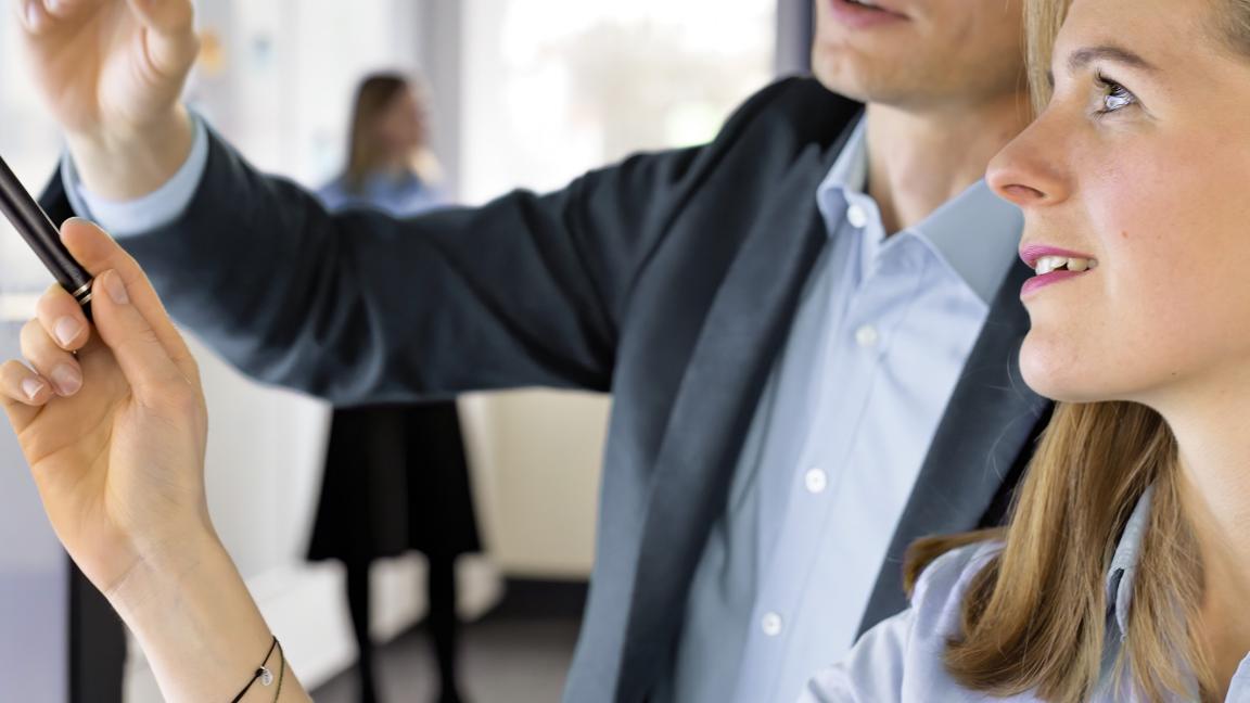 Digitalexpert:innen zeigen etwas an einem Whiteboard