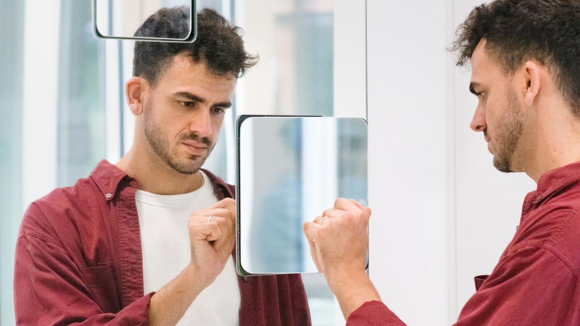 Mann interagiert mit seinem Spiegelbild vor einer Installation