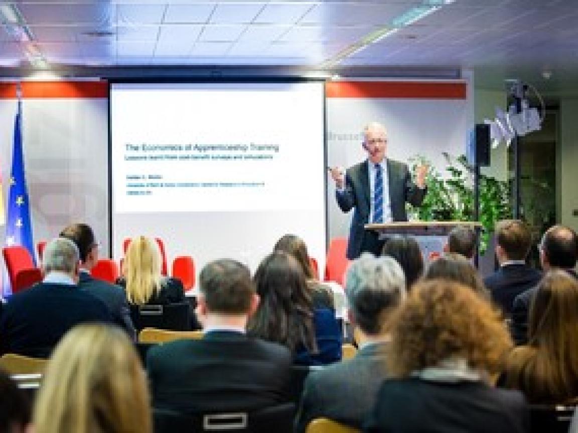 Mann steht auf einer Bühne und redet zu einem Publikum