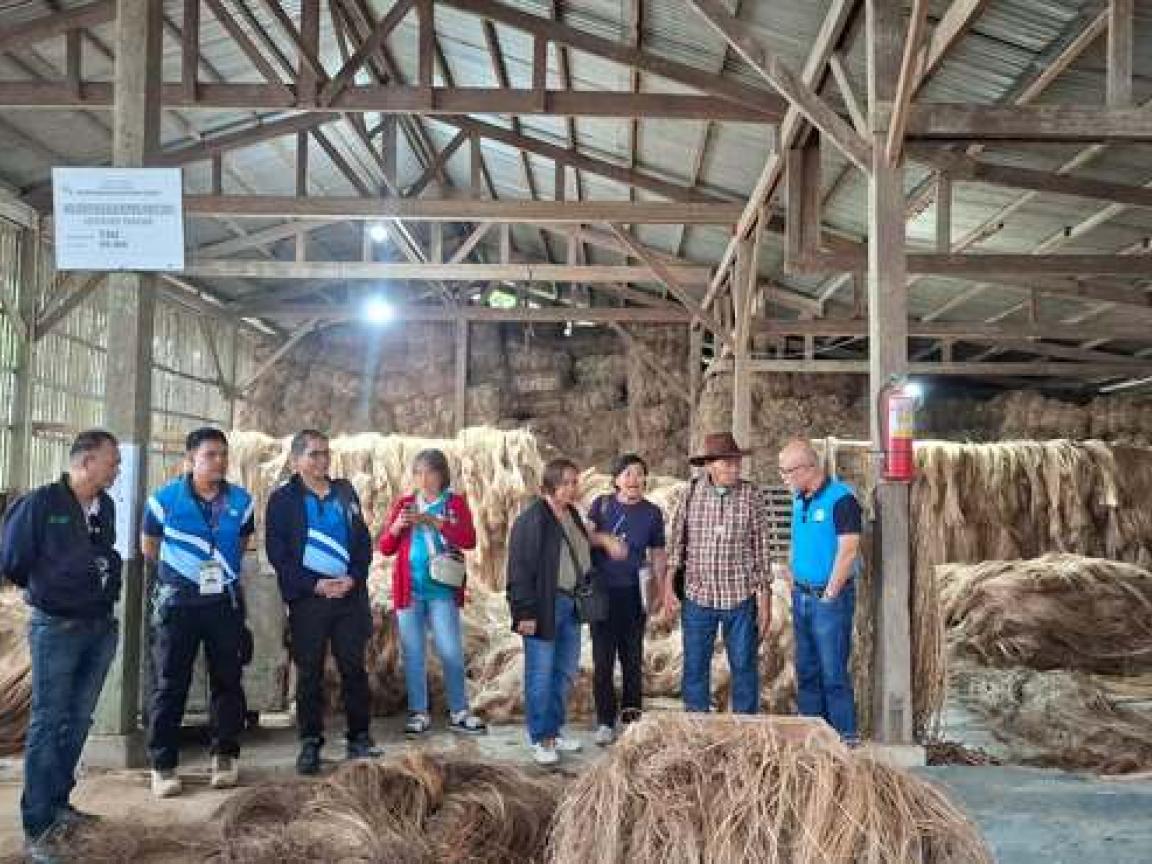 Vertreter:innen des Farmers Alternative for Self-Reliance Multi-Purpose Cooperative (FARSMCO) und GIZ in einer Scheune zwischen Strohballen.