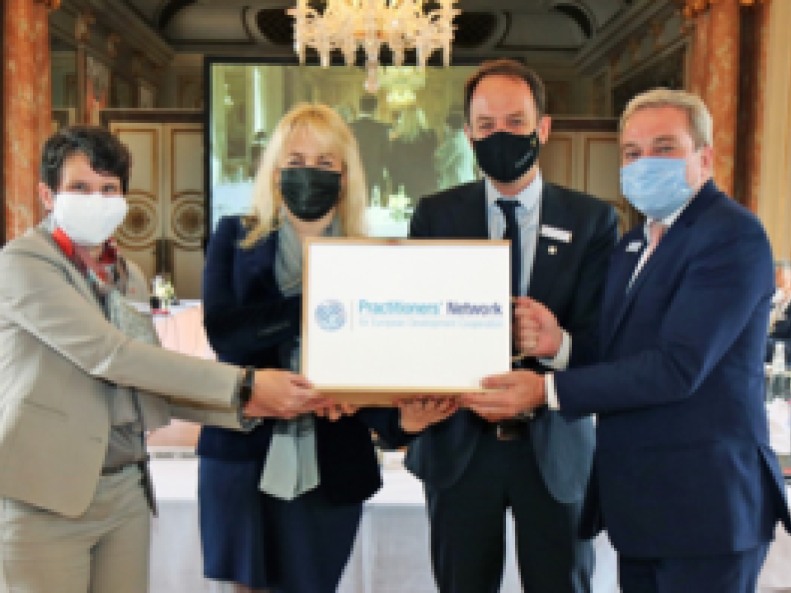Vier Personen mit Gesichtsmasken halten ein Schild hoch