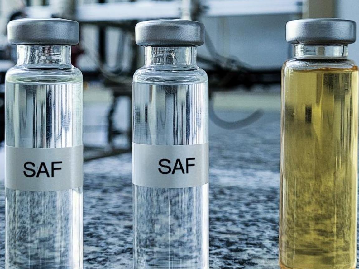 Mehrere Glasfläschchen mit Flüssigkeiten in verschiedenen Farben, beschriftet mit "SAF", stehen in einer Reihe auf einer Granitplatte in einem Laborumfeld.