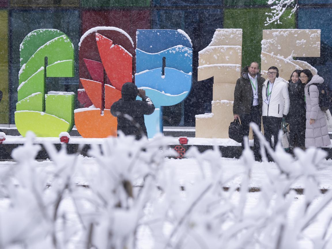 A group of people are photographed in front of a COP15 display.