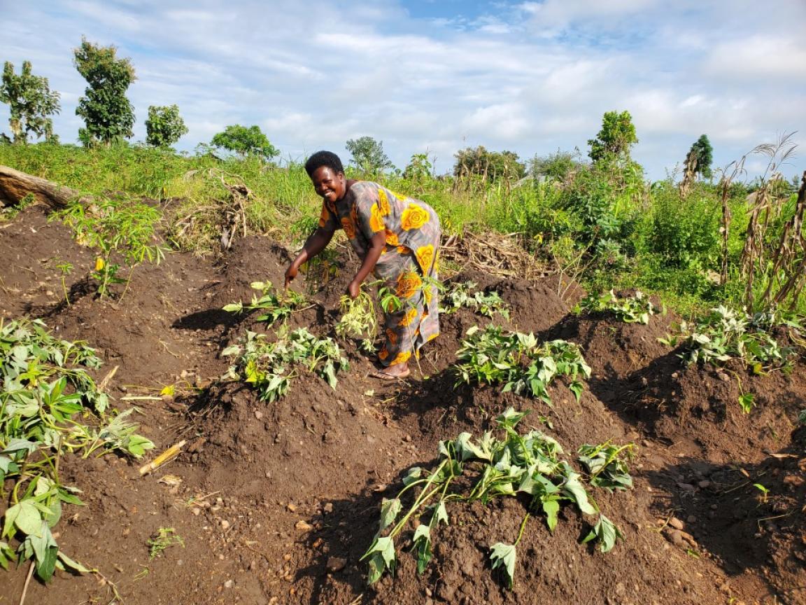 A woman stands in a field of crops and smiles.