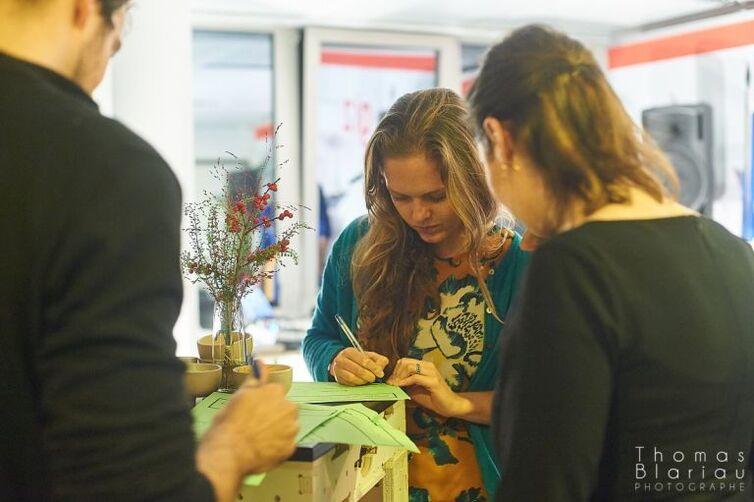 Drei Personen schreiben auf einen grünen Zettel