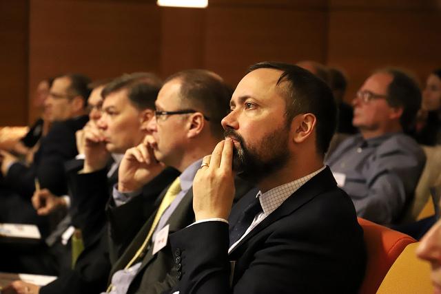 Personen sitzen nebeneinander in einem Saal