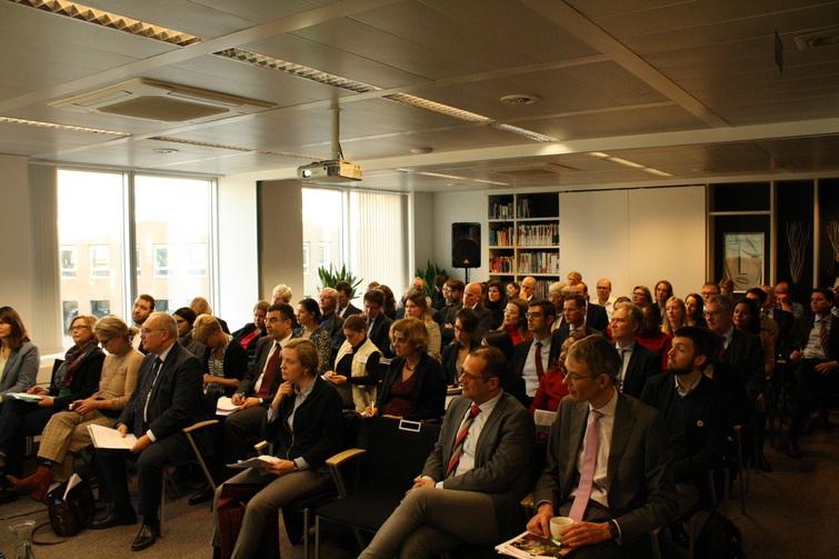 Viele Personen sitzen auf Stühlen verteilt in einem Raum