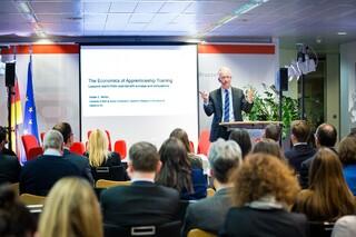 Mann steht auf einer Bühne und redet zu einem Publikum