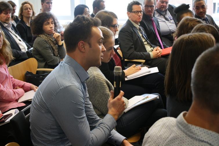 Mann in einem Publikum hält ein Mikrofon