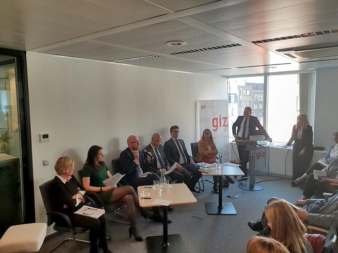 Viele Personen sitzen auf Stühlen vor einem Publikum