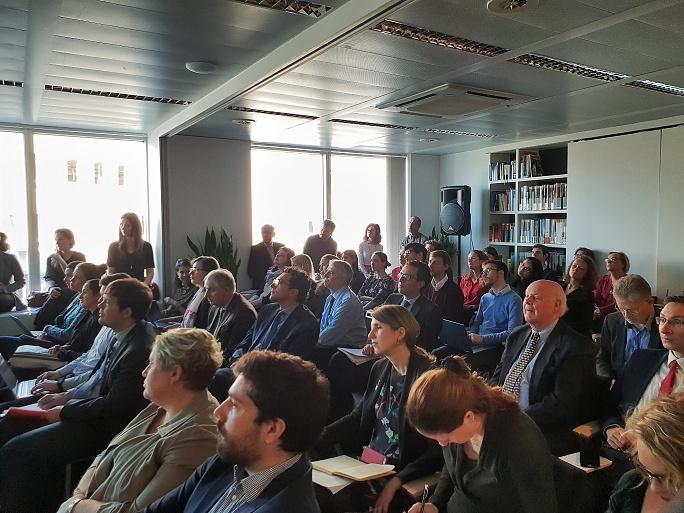Viele Menschen sitzen nebeneinander auf Stühlen