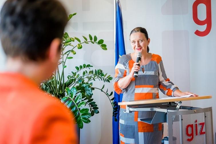 Frau mit Mikrofon in der Hand schaut eine gegenüberstehende Person an