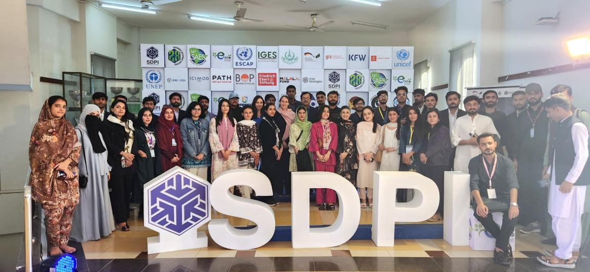 A large group of young men and women stand together for a photo, in front of a SDC media wall displaying partner logos.