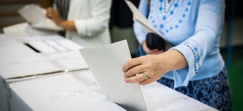 Eine Person gibt bei einer Wahl einen Stimmzettel ab.