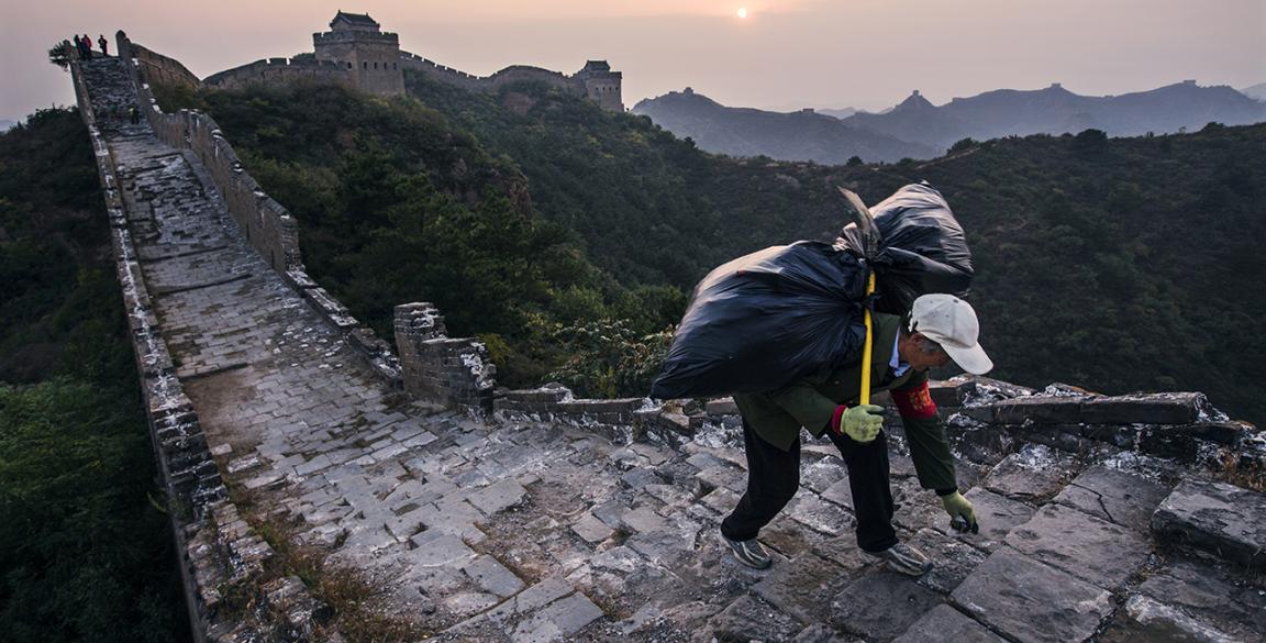A man carries a sack on his back up the Great Wall of China.
