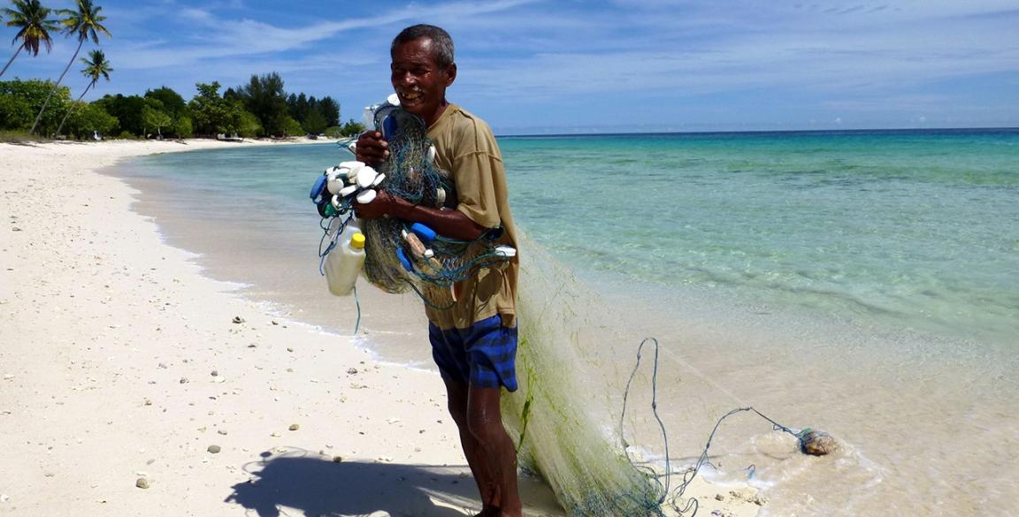 A man collects rubbish on the beach.