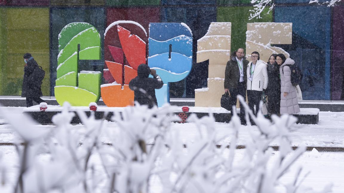 A group of people are photographed in front of a COP15 display.