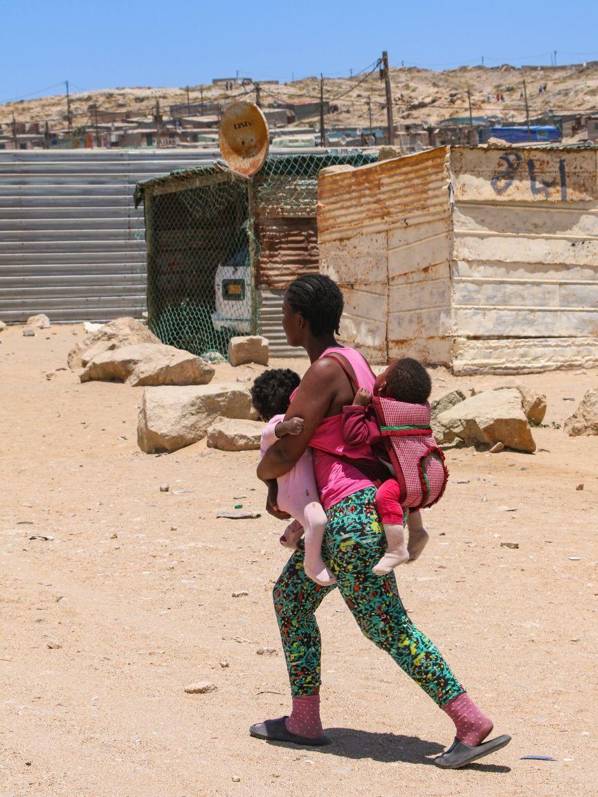 Woman carrying two children in a baby carrier