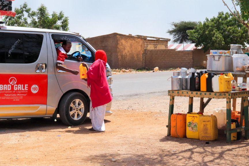 Woman hands milk canister to delivery driver