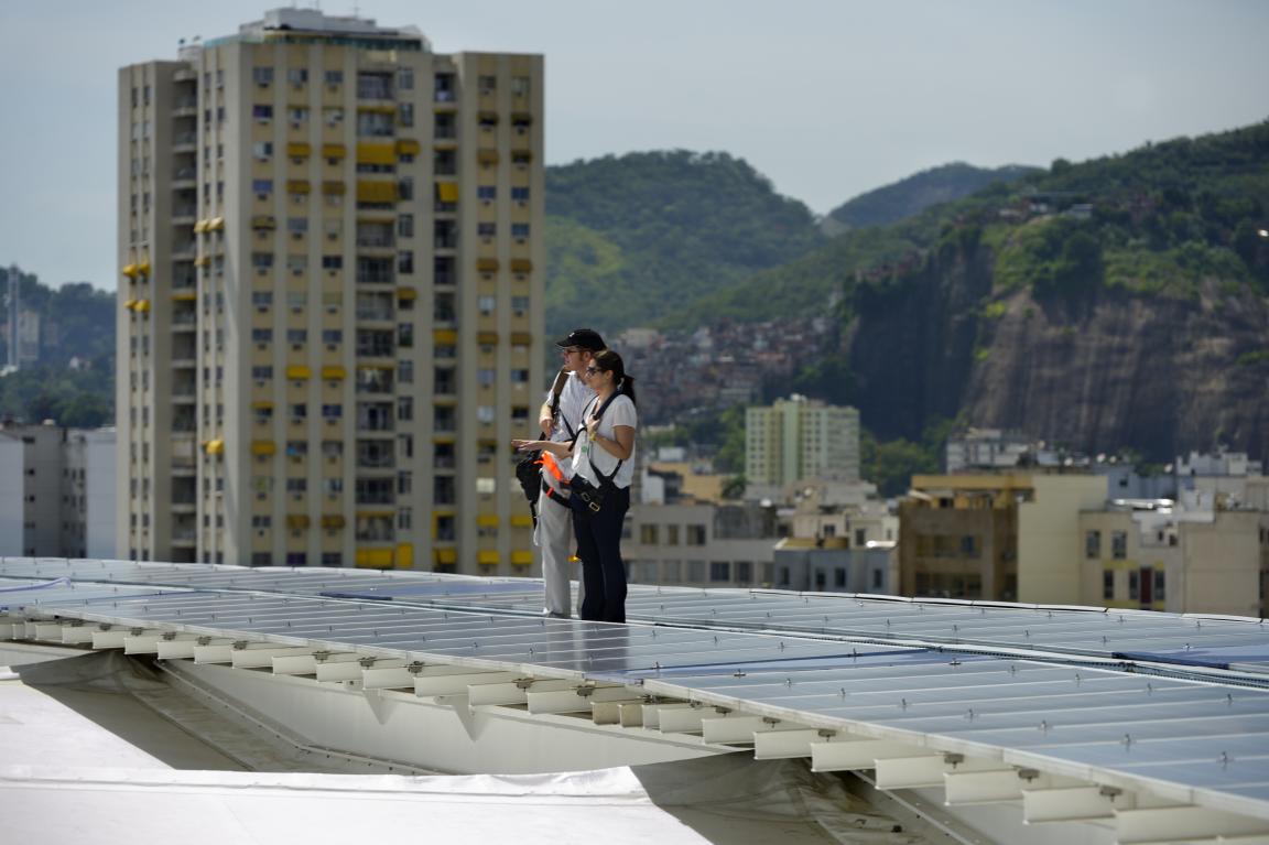 Two people beside the photovoltaic panels on the roof of Brazil’s Maracanã football stadium. 