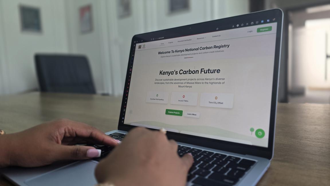 Die Startseite des kenianischen Kohlenstoffregisters auf einem Laptopbildschirm in einem Büro mit zwei tippenden Händen.
