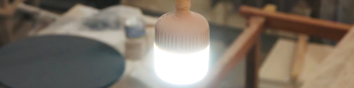 Una bombilla luminosa de bajo consumo cuelga sobre un banco de trabajo.