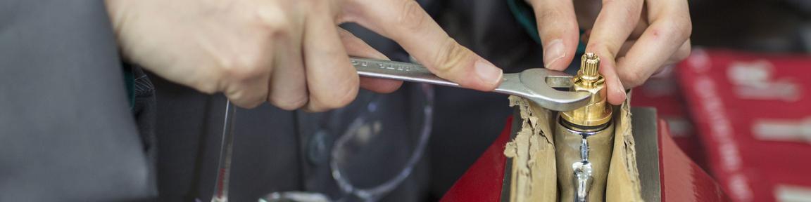 Eine Person repariert etwas mit einem Schraubenschlüssel