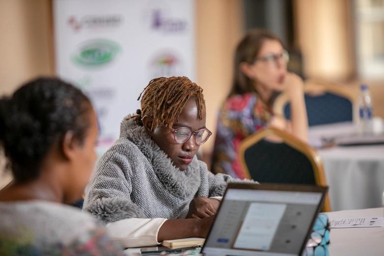 Drei Frauen sitzen an Tischen.