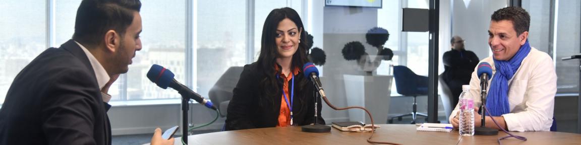 Une personne assise à une table avec des microphones.