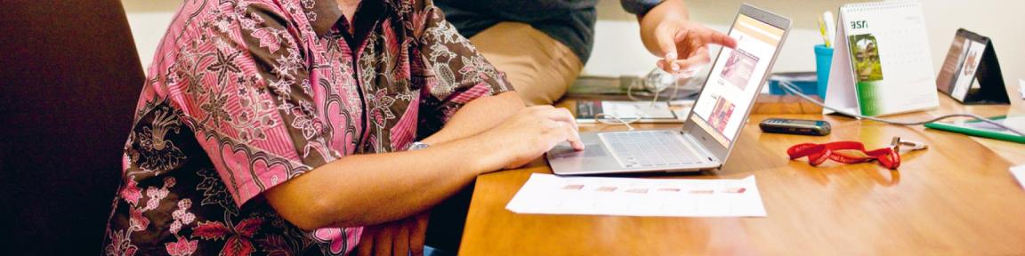 Žena sjedi za stolom sa laptopom.