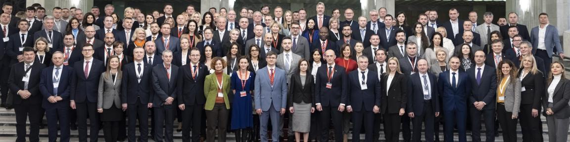 Un grup mare de oameni în rochie formală pozează pentru o fotografie.