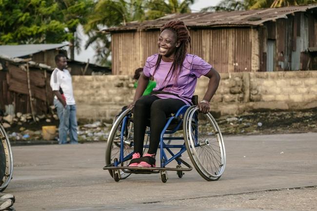 A smiling woman uses a wheelchair.