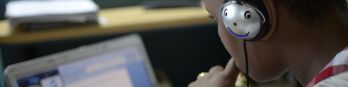 Garçon équipé d'écouteurs devant un ordinateur portable