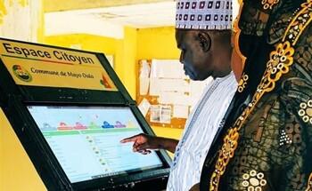 An elderly man taps his finger on the monitor of a large vending machine.