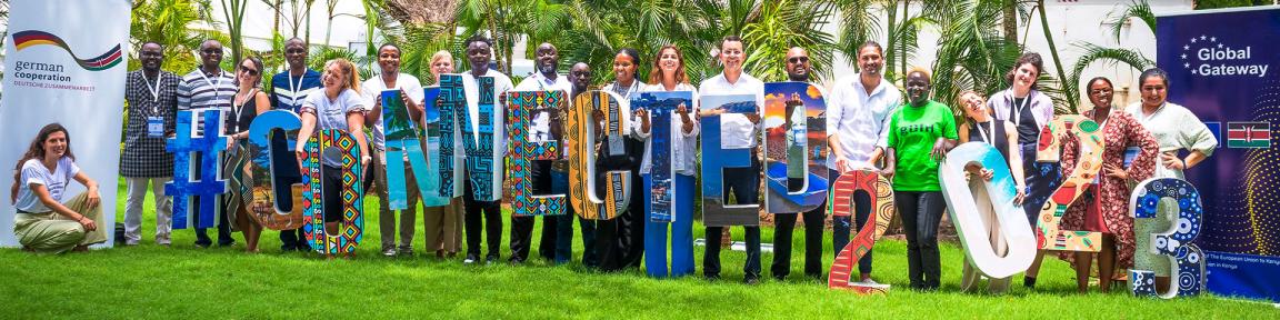 Eine Gruppe von Menschen steht auf einer Wiese und hält Buchstaben hoch, die das Wort „#Connected2023“ ergeben.