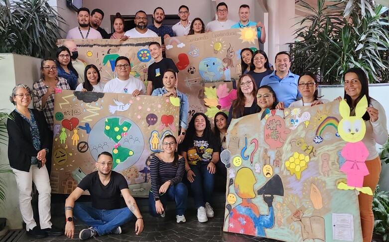Jóvenes y representantes del consejo consultivo juvenil posan juntos sosteniendo pósteres coloridos.