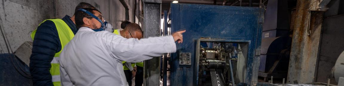 Un groupe de personnes se trouve à côté d'une machine dans une usine.